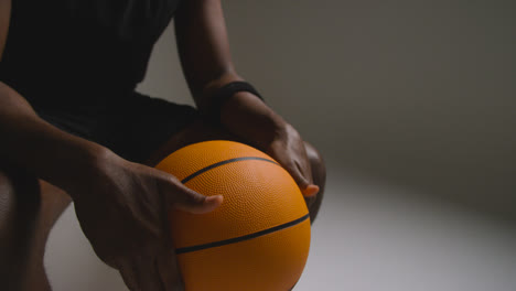 Nahaufnahme-Eines-Sitzenden-Männlichen-Basketballspielers-Mit-Händen,-Die-Ball-5-Halten